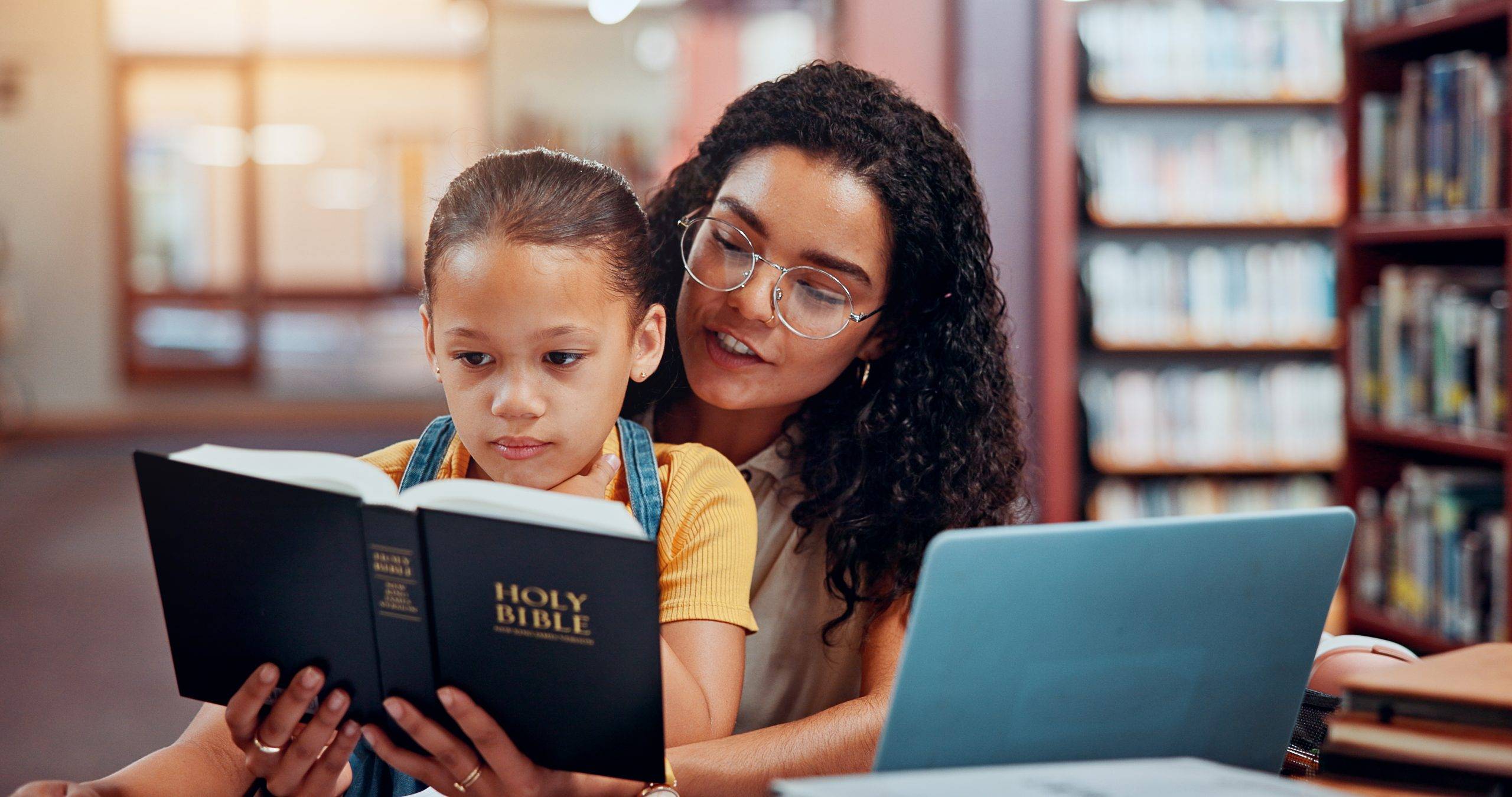 Teacher, child and reading bible for learning story, knowledge or education support in library. Christian school, spiritual guide or teaching kid with storytelling or holy scripture, god or history.